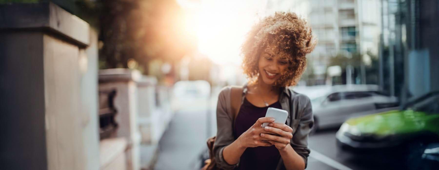 a young woman looking at her smart phone whole outside in a city environment