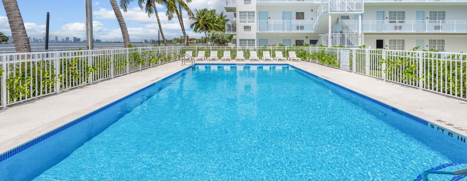 a swimming pool with palm trees and a building in the background