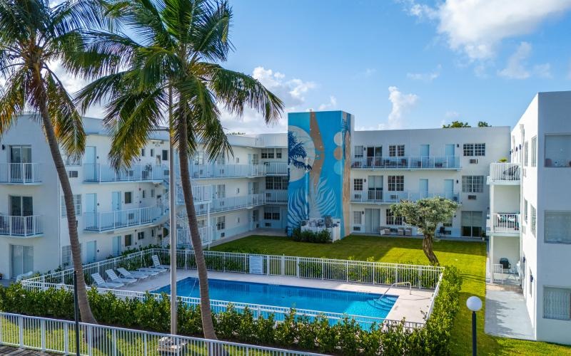 a swimming pool and palm trees in front of a large building